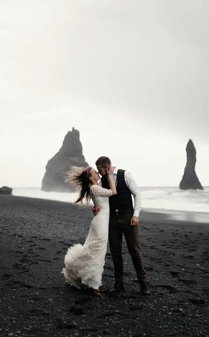 Pasangan pengantin di pantai pasir hitam saat senja
